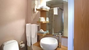 Ein Badezimmer mit Toilette, Waschbecken, Spiegel, Handtuchhalter und Duschbereich.