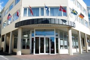 A building with a curved entrance, flags, and a glass facade.
