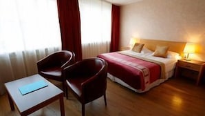 Ein Hotelzimmer mit einem Bett, zwei Stühlen, einem Nachttisch und einer Lampe.