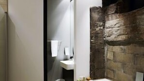 Ein Badezimmer mit Steinwand, Waschbecken und Spiegel.