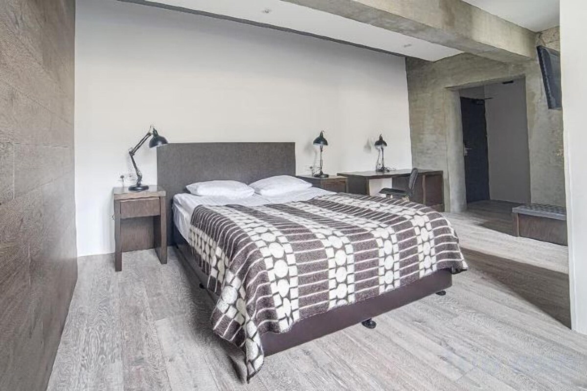 A modern bedroom with a large bed, two bedside tables, and a nightstand.