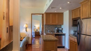 A modern kitchen with granite countertops, wooden cabinets, a stainless steel refrigerator, and a built-in oven. - Sunrise & Sunset Views – 2BR Condo in a Prime Location (Puerto Vallarta)