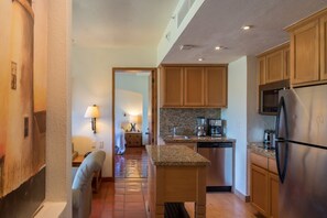A modern kitchen with granite countertops, wooden cabinets, a stainless steel refrigerator, and a built-in oven.