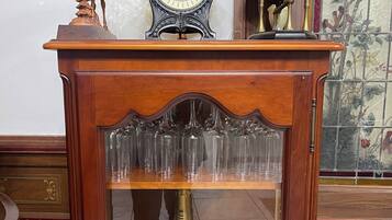 A wooden table with a glass shelf holding a champagne bottle and glasses.