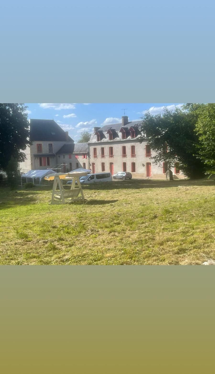 Ein Gebäude mit vielen Fenstern und einer Grünfläche davor.
