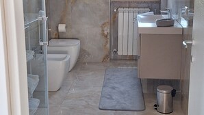 Une salle de bain équipée de toilettes, d’un bidet, d’un lavabo et d’un miroir.