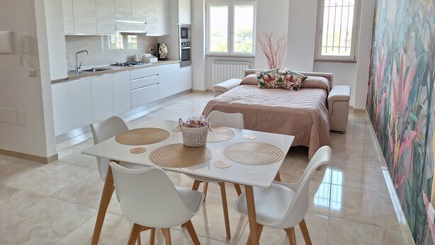 Une cuisine moderne avec des meubles blancs et un coin repas comprenant une table et des chaises.