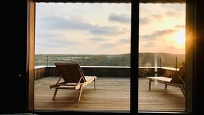 A wooden deck with two lounge chairs facing a scenic view of a beach and hills during sunset. - Villa Alduna, just few steps from the beach (Capbreton)