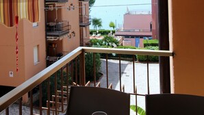 Un balcón con vistas a la costa, donde se distingue un edificio con balcones y un cielo despejado.