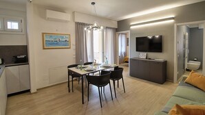 Un apartamento moderno con comedor, cocina, sala de estar y televisor montado en la pared.
