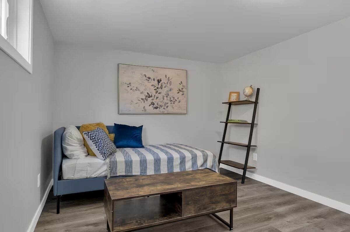 A room with a bed, a wooden coffee table, a blue sofa, and a wall-mounted shelf.
