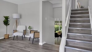 A modern living room with a staircase, a dining area, and a view of the outdoors. - Niagara Family Stay | Near Brock, Falls & Wineries (Thorold)
