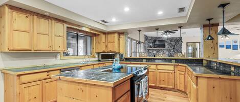 A spacious kitchen with wooden cabinets, a large island, and a stone backsplash.