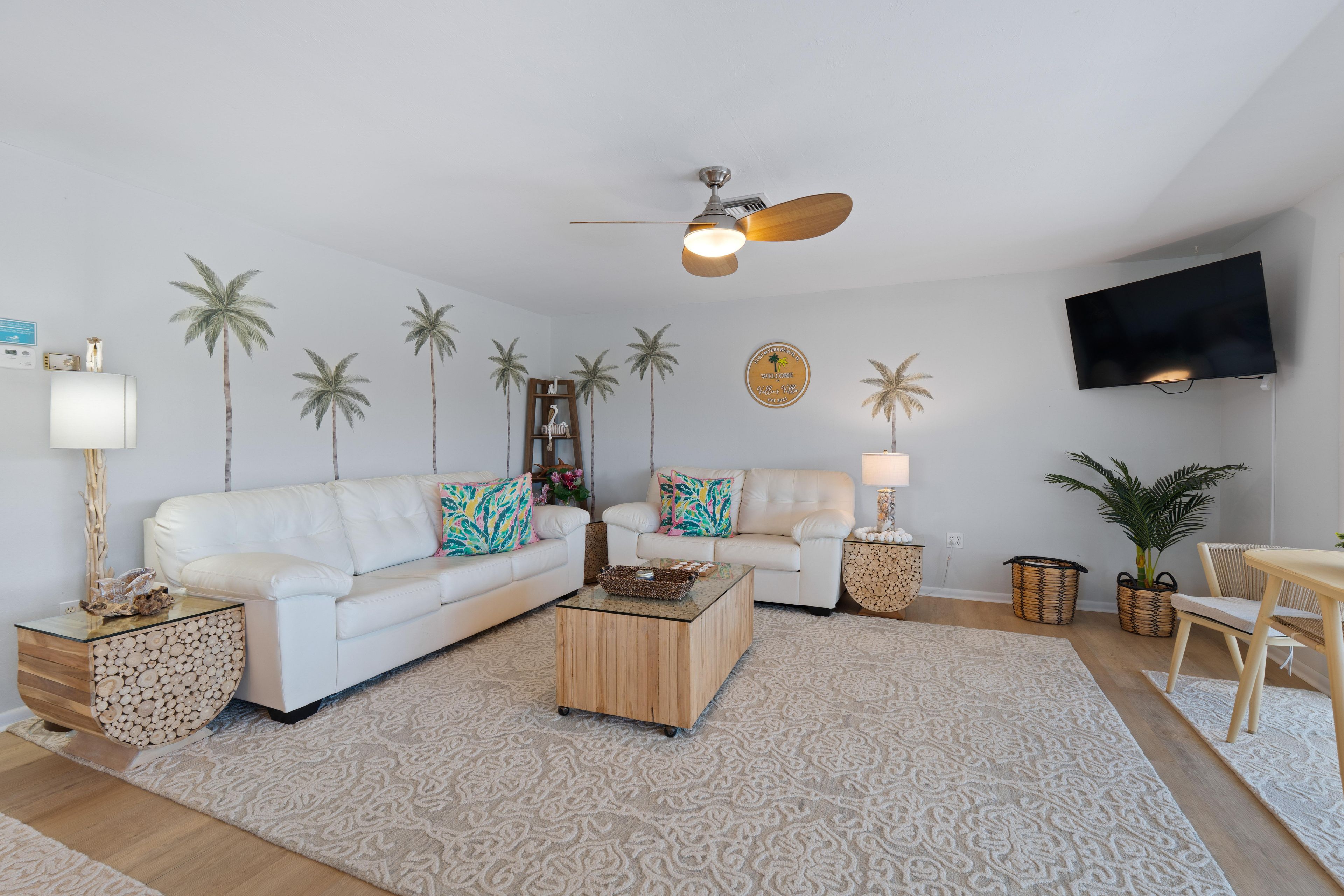 A modern living room with a white sofa, a coffee table, and a ceiling fan.