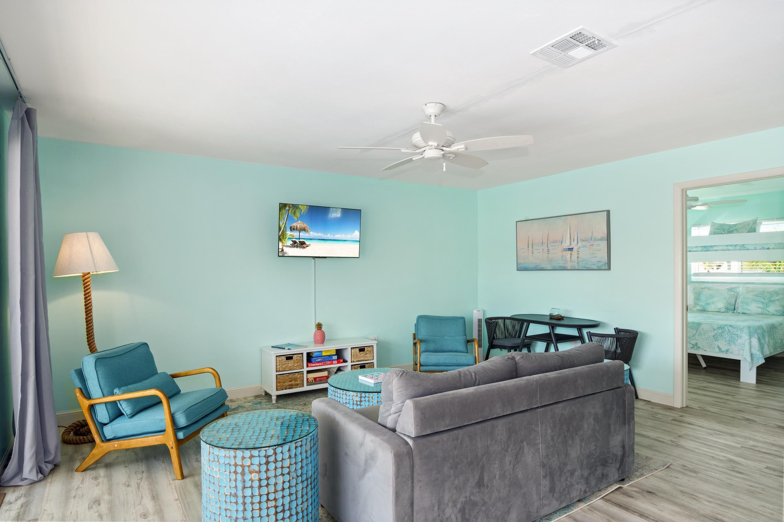 A living room with a sofa, chairs, a coffee table, a TV, and a ceiling fan.