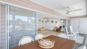 Une vaste terrasse dotée d’une table à manger, de chaises et d’un ventilateur de plafond.