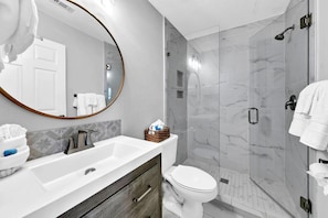 A modern bathroom with a white sink, a mirror, a toilet, and a shower area. - Beachside Villas 1121 (Santa Rosa Beach)