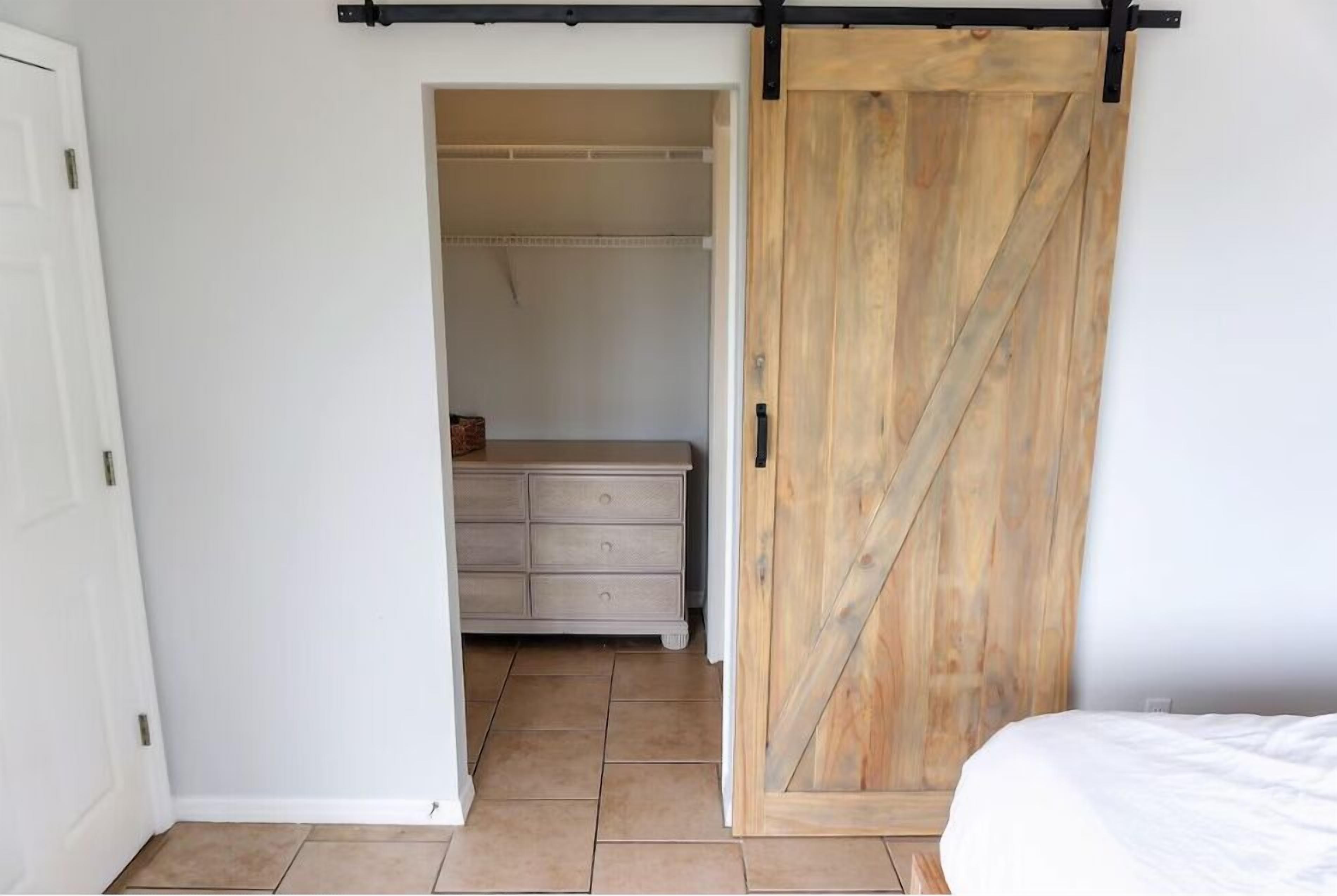 A bedroom with a wooden sliding door, a white dresser, and a bed.