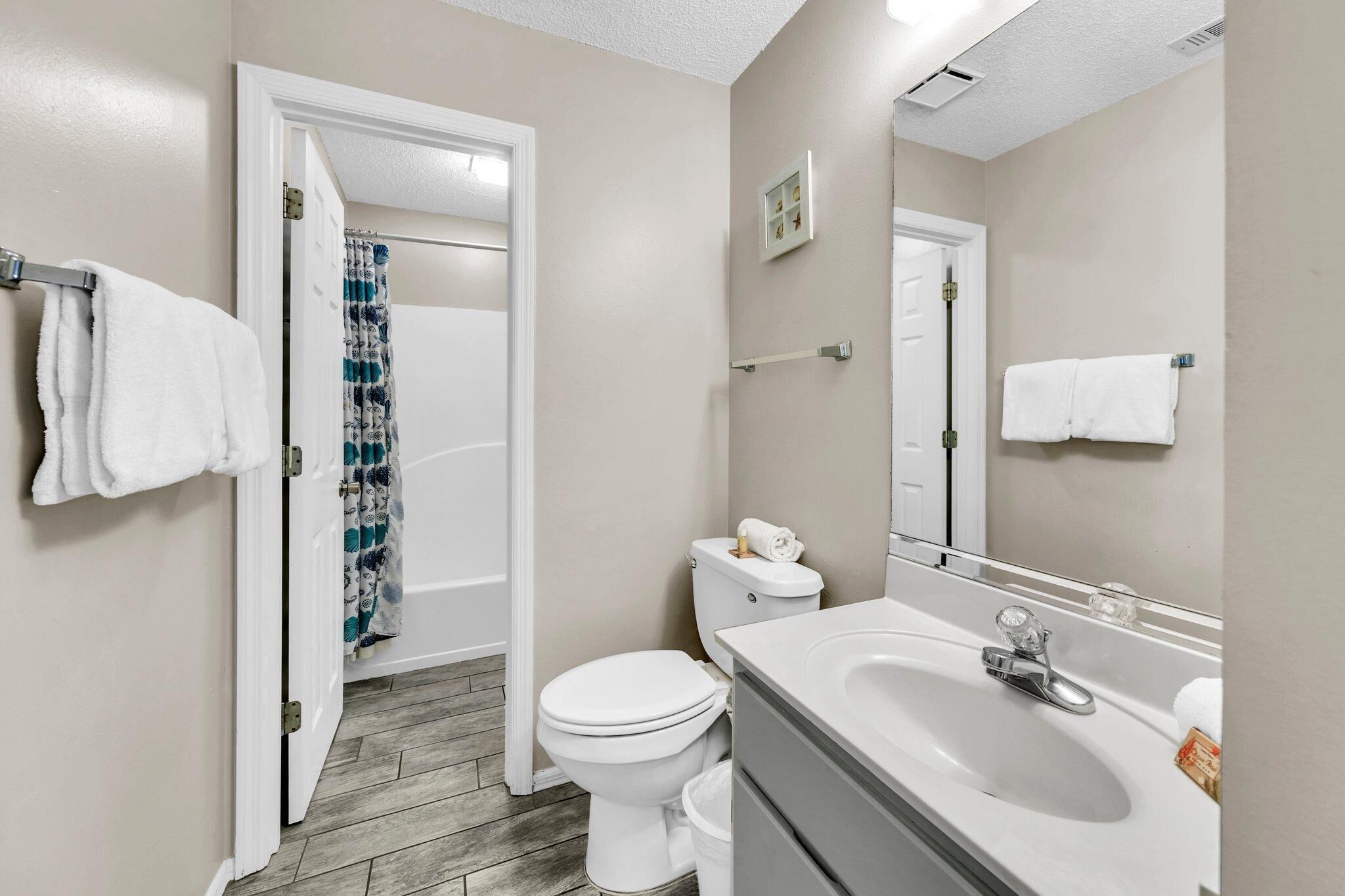 A bathroom with a toilet, sink, and shower curtain.