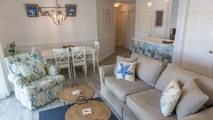 Una sala de estar con un sofá, dos sillones, una mesa de centro y una mesa de comedor con sillas.