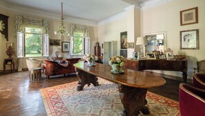 A spacious room with a large wooden dining table, comfortable seating, and a view of the outdoors through large windows. - Stunning Venetian Villa, with pool, set in a private park in the Euganean Hills (Este)