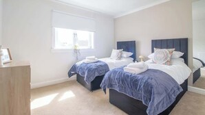 A bedroom with two beds, a window, a bedside table, and a mirror. - Leven Loft -  2 Bed Flat in Coatbridge (Coatbridge)