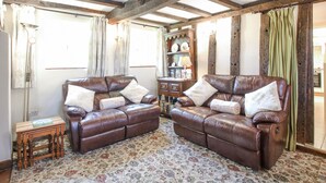 Une pièce comprenant deux canapés en cuir, une table d’appoint en bois et un tapis à motifs.