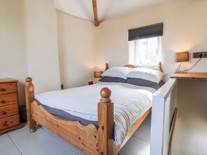 A bedroom with a wooden bed, a nightstand, a dresser, and a window with a view. - Tadworthy Tower (Bideford)