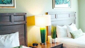 A hotel room with a wooden headboard, a bedside table with a lamp, a vase with plants, and a bed with white bedding. - Orange Lake Holiday Inn Resort 2 Bedroom Villa In Beautiful Orlando/Kissimmee (Kissimmee)
