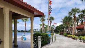 A covered walkway with palm trees and flags, leading to a building with a red roof. - Orange Lake Holiday Inn Resort 2 Bedroom Villa In Beautiful Orlando/Kissimmee (Kissimmee)