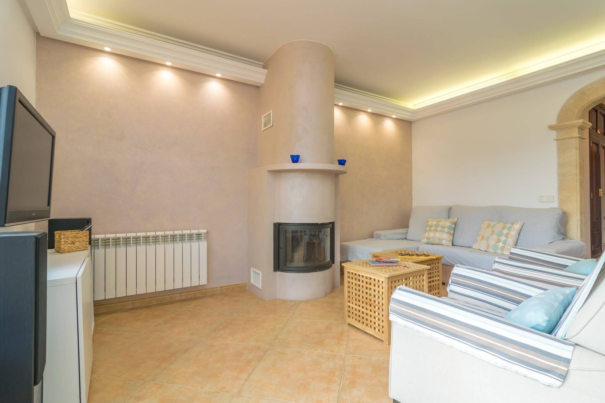 Ein Wohnzimmer mit Kamin, einer Couch, einem Fernseher und einer Heizung.