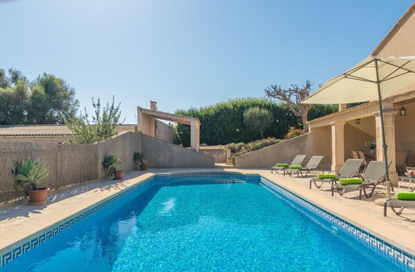 Una piscina con sillas de descanso y una pérgola.