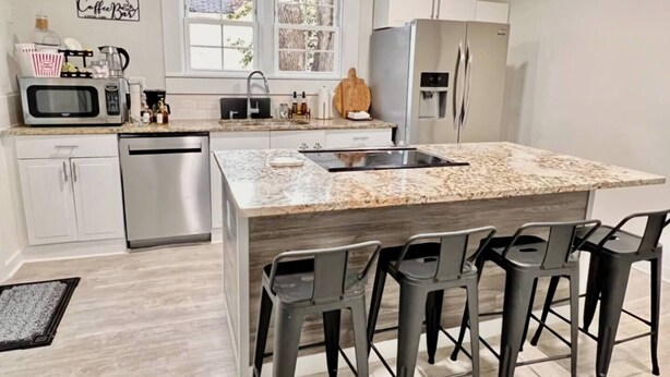 A modern kitchen with a central island, stainless steel appliances, and bar stools. - HP@The Cottage|Spectrum|Bojangles|NODA|Dogs|Yard (Charlotte)