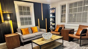A modern living room with a grey sofa, brown leather armchair, and a wooden coffee table. - HP@The Cottage|Spectrum|Bojangles|NODA|Dogs|Yard (Charlotte)