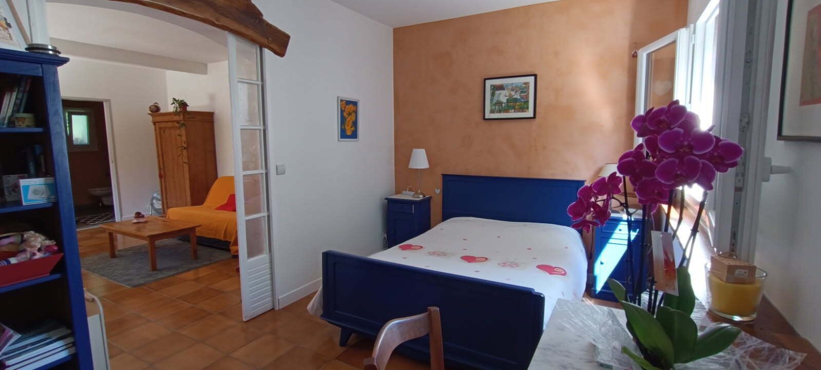 Un dormitorio con cama, escritorio, silla, estantería y ventana con vistas.