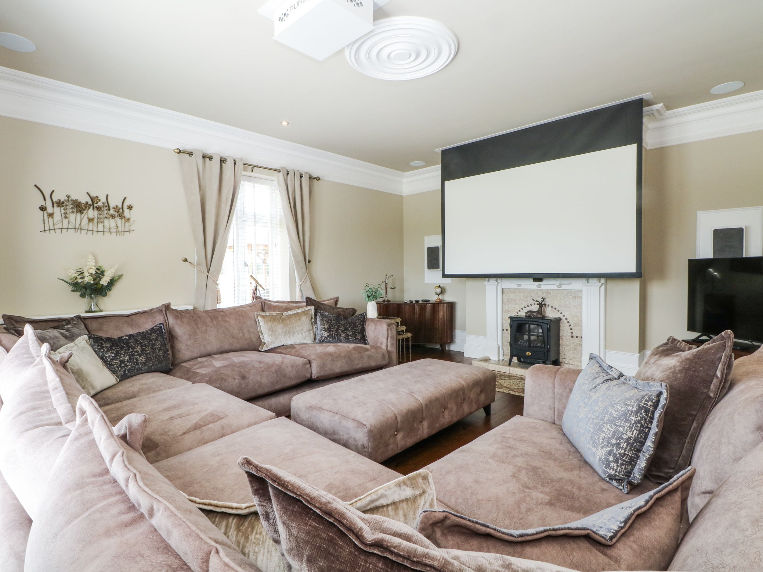 A living room with a sectional sofa, a fireplace, a television, and a decorative wall piece.