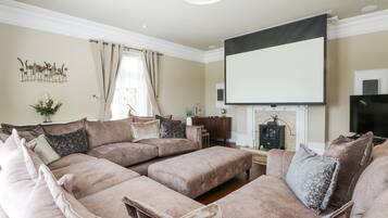 A living room with a sectional sofa, a fireplace, a television, and a decorative wall piece.