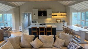 Una cocina amplia con una isla central, iluminación colgante y vistas amplias a través de ventanas grandes.