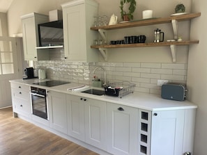 Une cuisine moderne avec des meubles blancs, une cuisinière noire, un évier et un grille-pain.