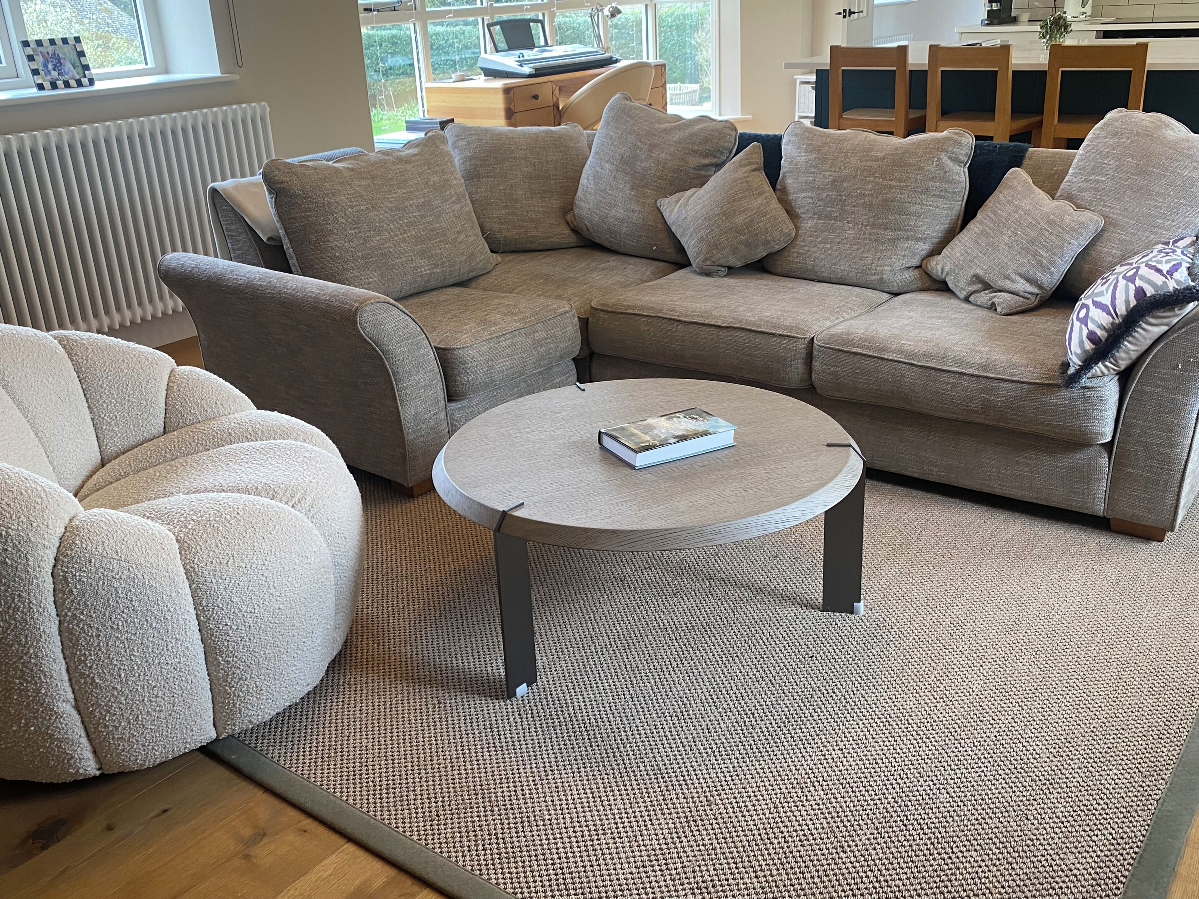 A living room with a sectional sofa, a round coffee table, and a patterned rug.