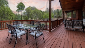 A wooden deck with a glass table and chairs, surrounded by a wooden railing. - European Rustic Mountain Retreat in Torreon (Show Low)