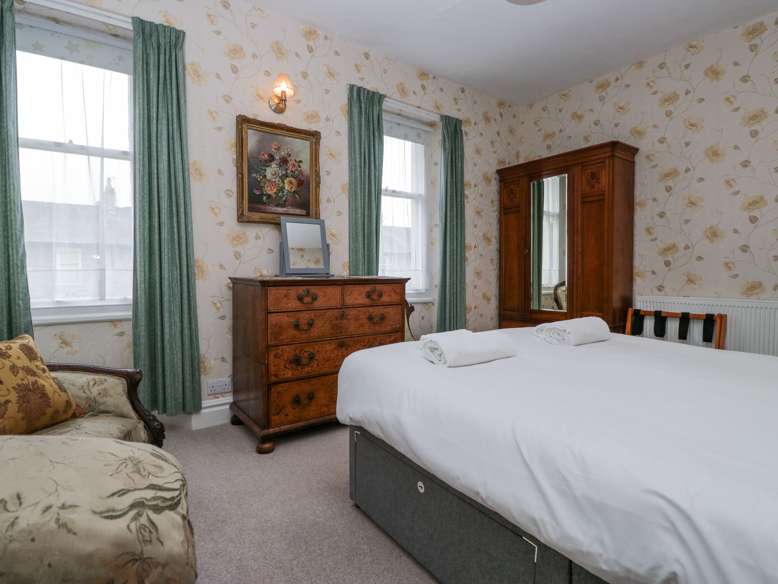 Une chambre à coucher avec un lit, une commode, une chaise et un miroir.