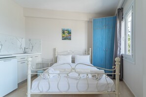 A bedroom with a bed, a wardrobe, a desk, and a painting on the wall. - Apartment 'Quadruple  4' with Sea View, Wi-Fi and Air Conditioning (Nikiana)