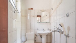 Uma casa de banho com sanita, lavatório e chuveiro.