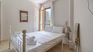 Quarto com cama, mesa de cabeceira, luminária e janela.