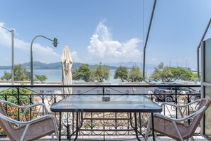 A balcony with a table and chairs, a view of the sea, and mountains in the distance. - Apartment 'Quadruple  4' with Sea View, Wi-Fi and Air Conditioning (Nikiana)