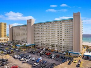 A large hotel with multiple floors and a parking lot in front.