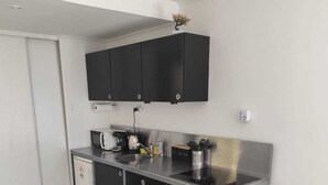 A modern kitchen with black cabinets, stainless steel appliances, and a wooden table.