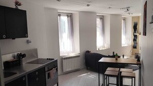 A modern kitchen with a central island, a dining area with a table and chairs, and a built-in oven.