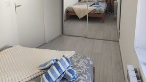 A bedroom with a bed, a mirror, and a person taking a photo.